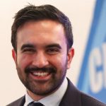 "Portrait of Zohran Mamdani smiling at public event"