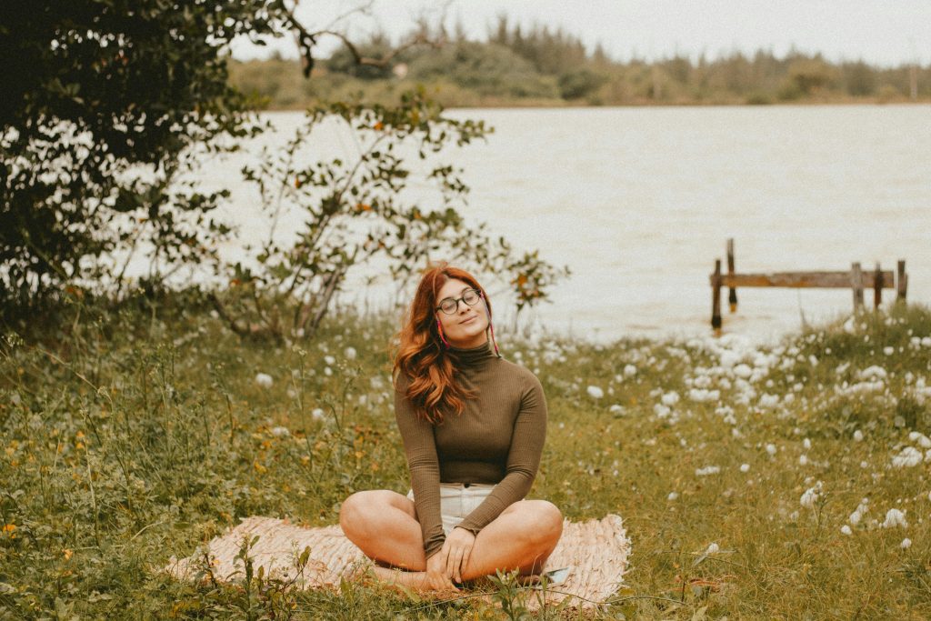 Woman practicing self-love through meditation in a peaceful natural setting