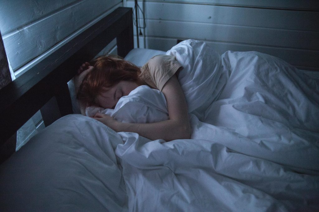 Person enjoying Weekend Catch-Up Sleep in morning sunlight, relaxed in bed